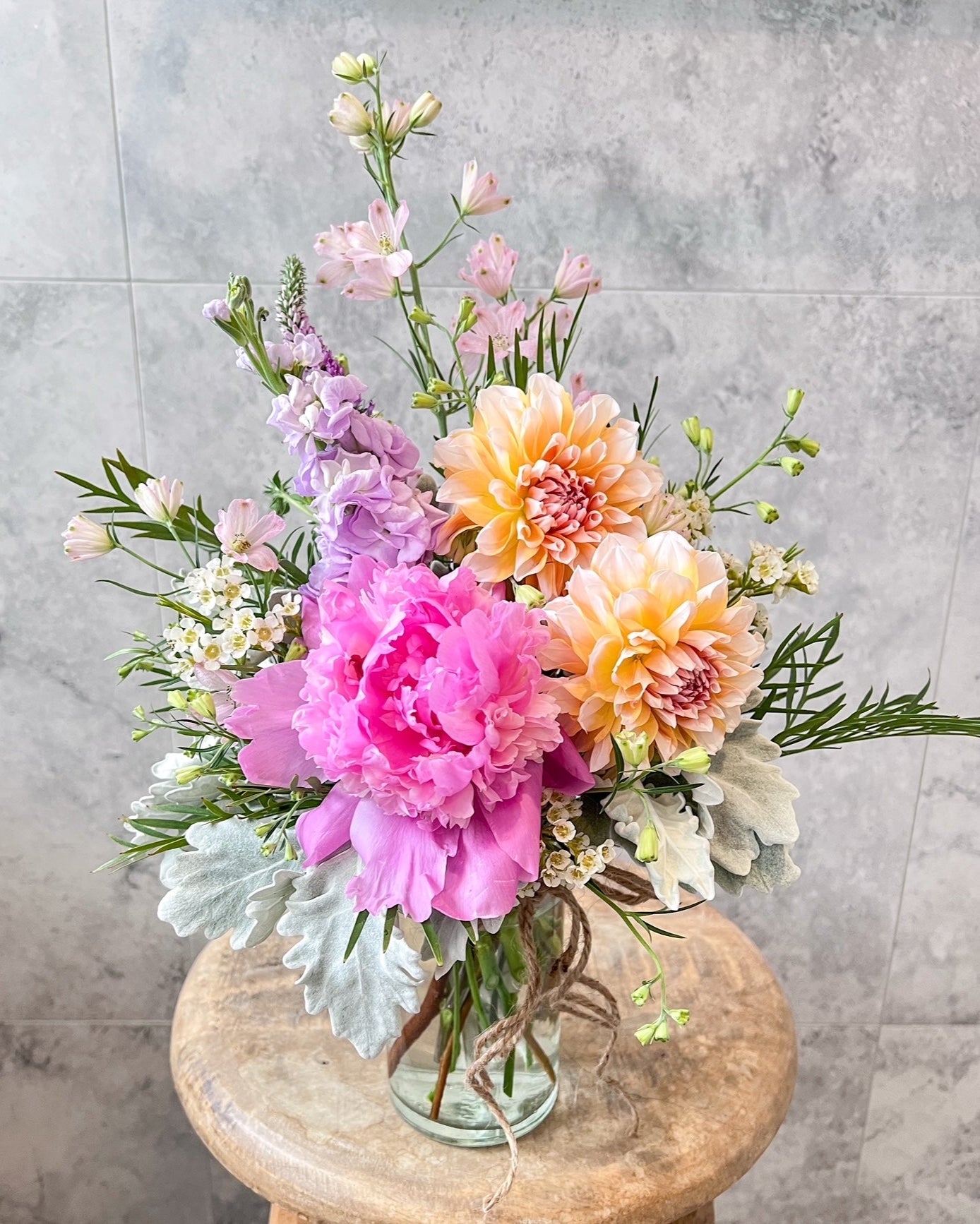 A pretty, jar arrangement of flowers including pink peony, dahlia and seasonal blooms, delivered fresh across Melton by The Flowered Heart