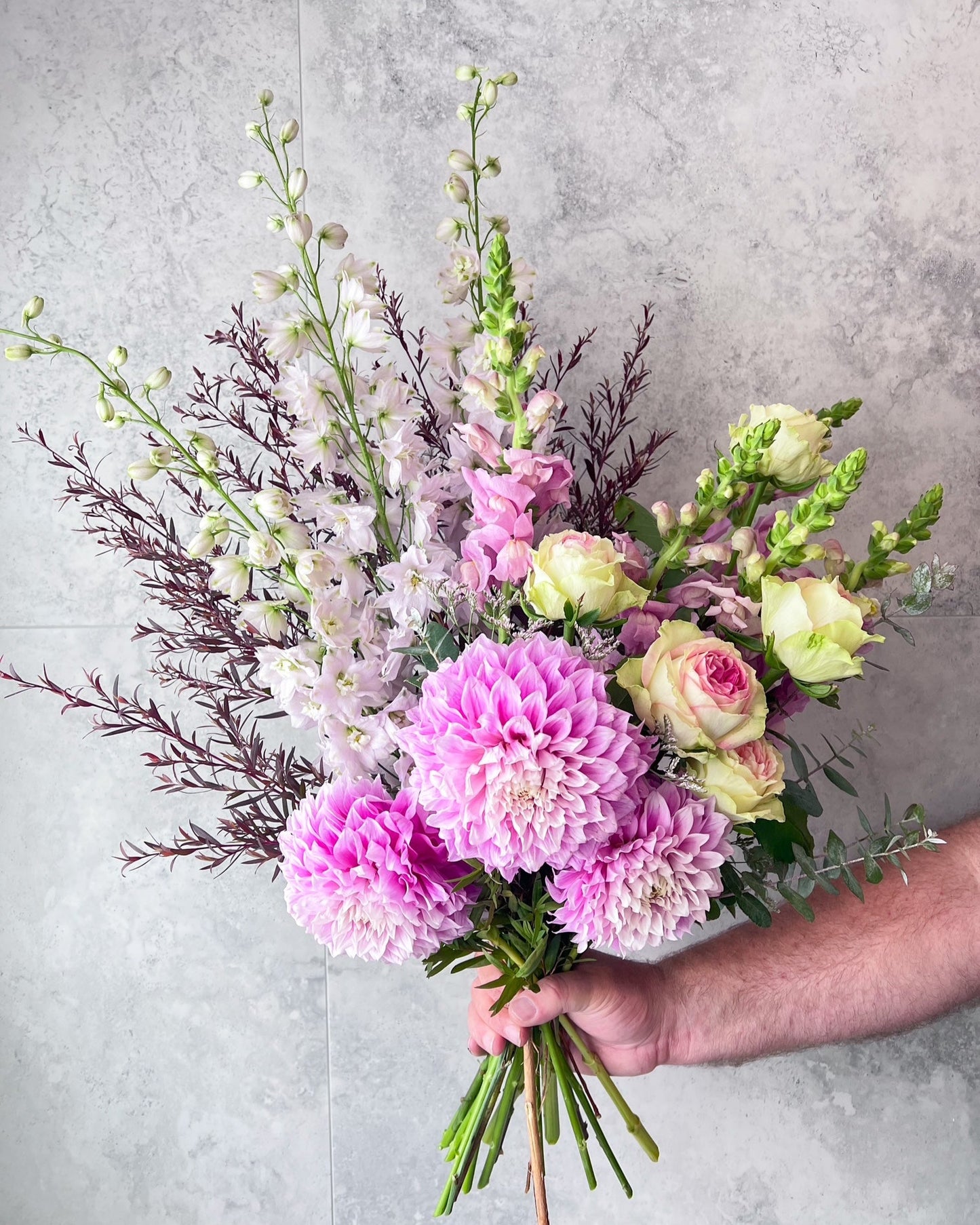A large hand-tied bouquet of pastel flowers including pink roses, delphinium, dahlia and seasonal blooms, delivered fresh across Melton by The Flowered Heart