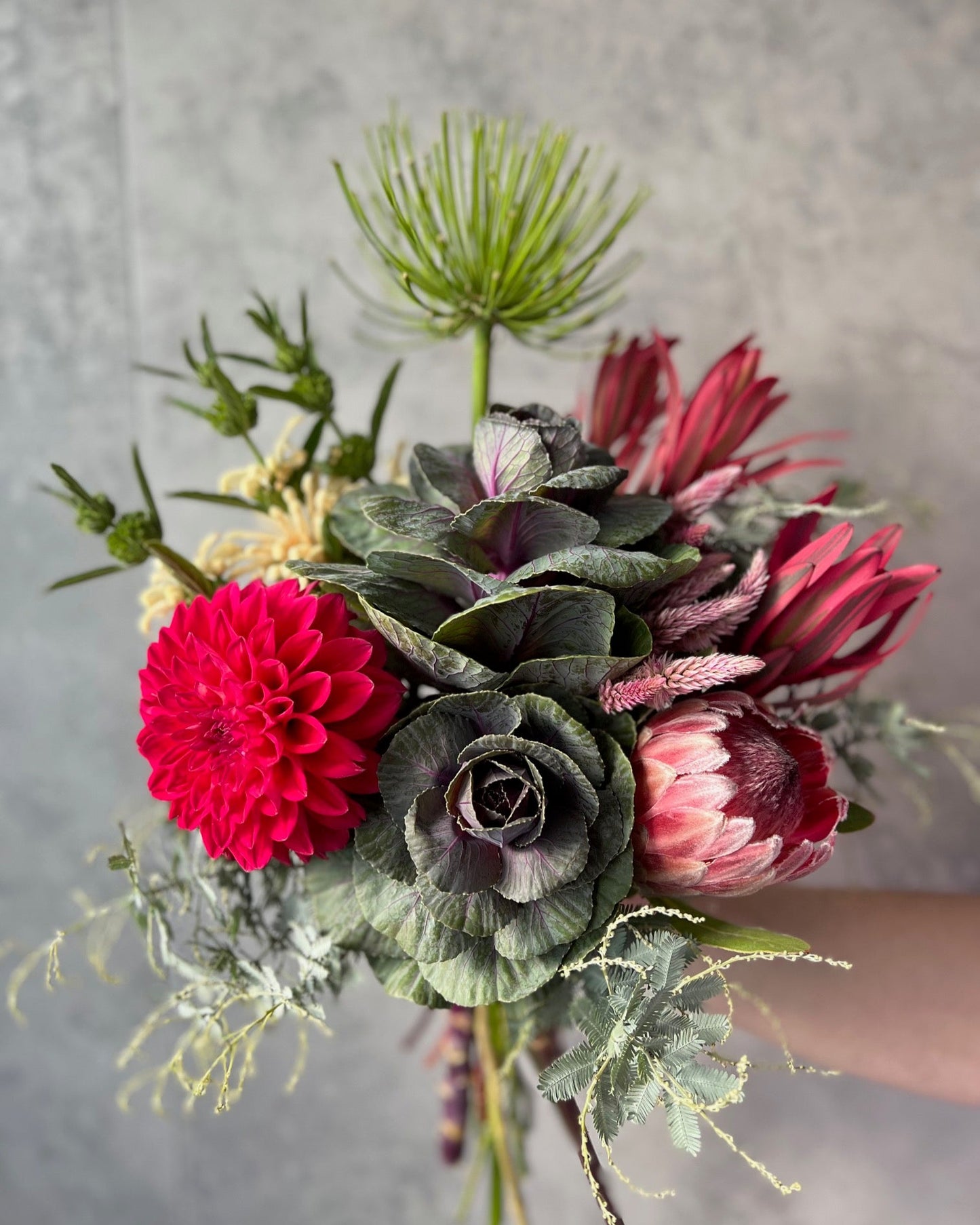 A bold and creative, hand-tied bouquet of stunning flowers including kale, protea, dahlia and seasonal blooms, delivered fresh across Melton by The Flowered Heart
