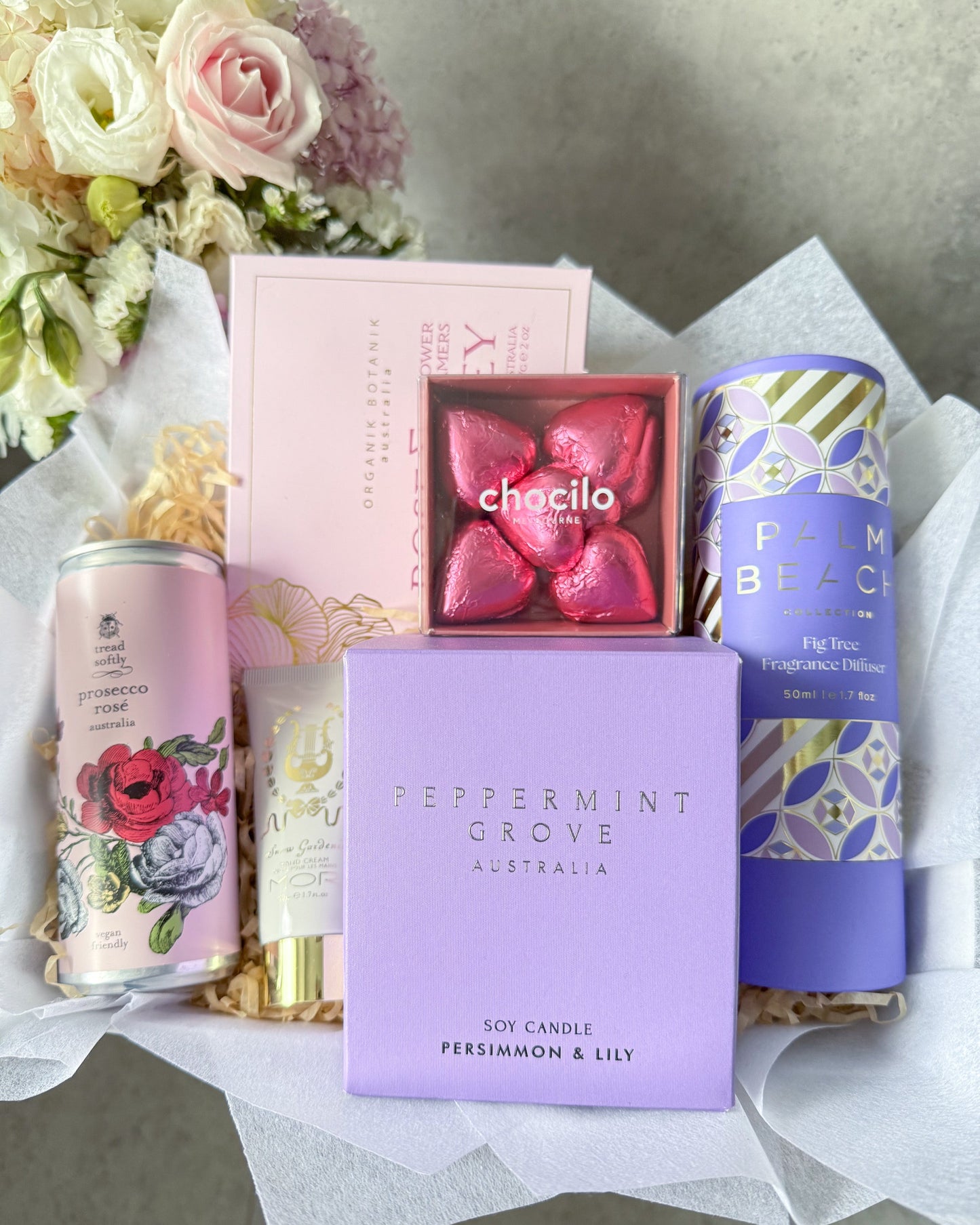 Sweet Things Gift Hamper featuring a persimmon and lily candle, Mor hand cream, Tread Softly Rose', Chocilo Chocolates, Palm Beach Diffuser and Organik Botanik Shower Steamers, beautifully presented in a gift hamper.