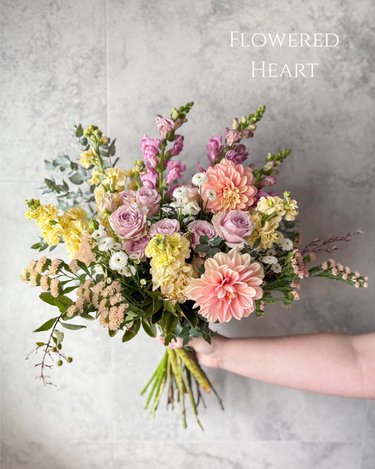 Our large sized Daily flower bouquet from our Flowers with Heart collection. It features a soft pastel palette and had peach dahlias, yellow stock, mauve snapdragons, spray roses and seasonal flowers.